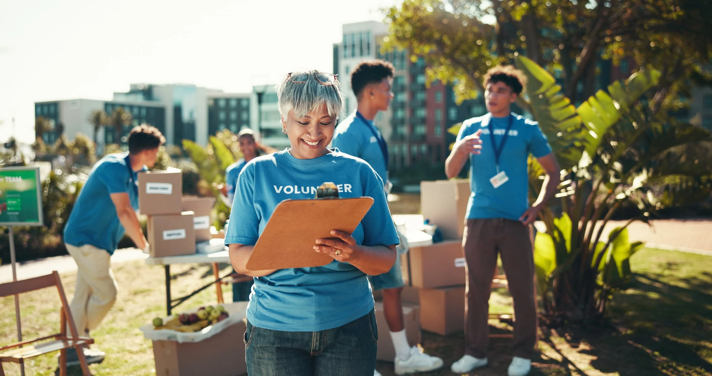 Volunteer in a blue shirt smiling while holding a clipboard at an outdoor event
